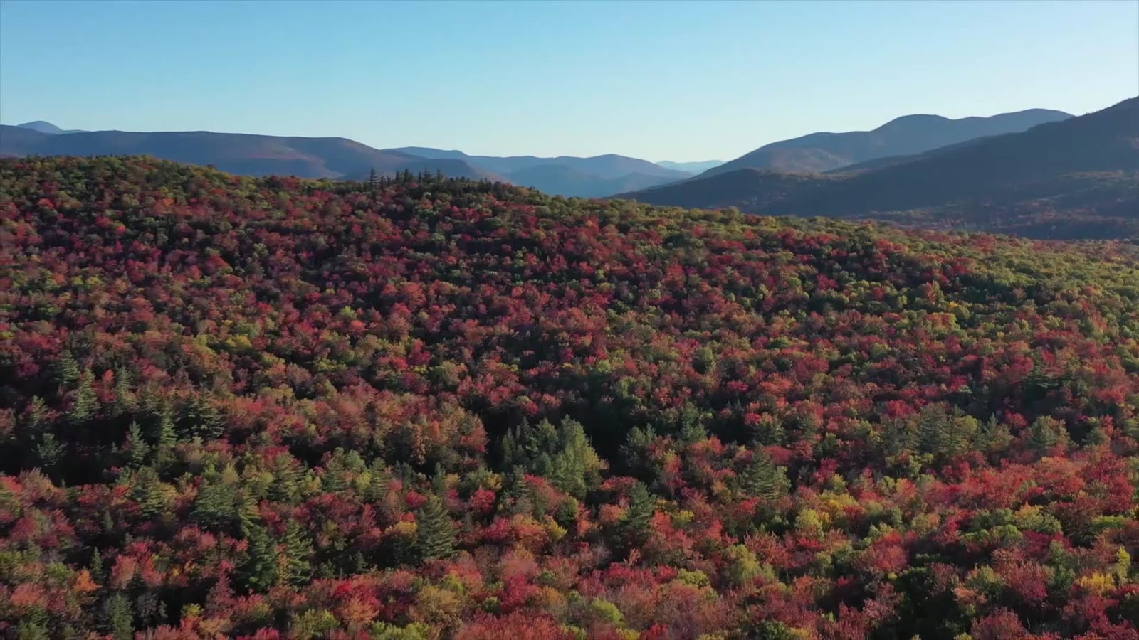 Fall foliage over wooded New England hills, illustrative